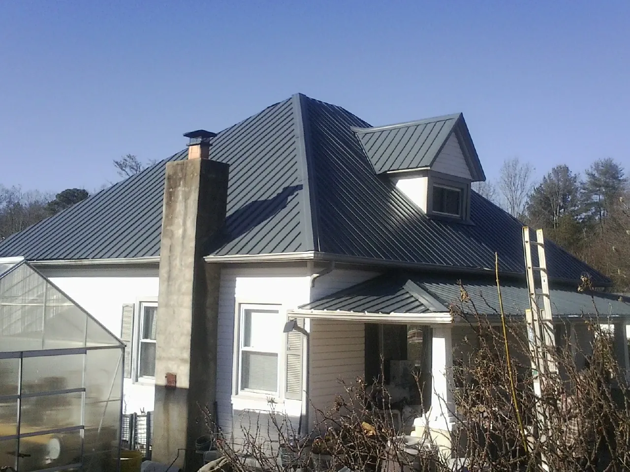 Dark blue standing seam metal roof on a white farmhouse with dormer — Slate & Tile Roof Repair by Roofing Brothers in Pocono Summit