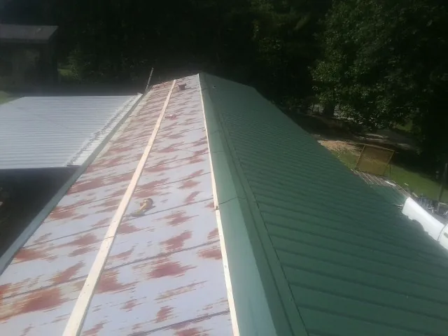 Old rusted panels beside newly installed green metal roofing — Wind Damage Roof Repair by Roofing Brothers in Pocono Summit
