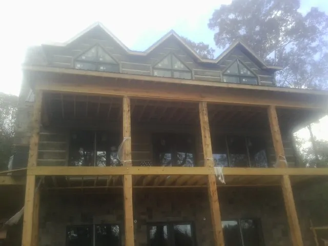 Dormers and porch framing on a large log home under construction — Roof Coating work by our crew in Pocono Summit
