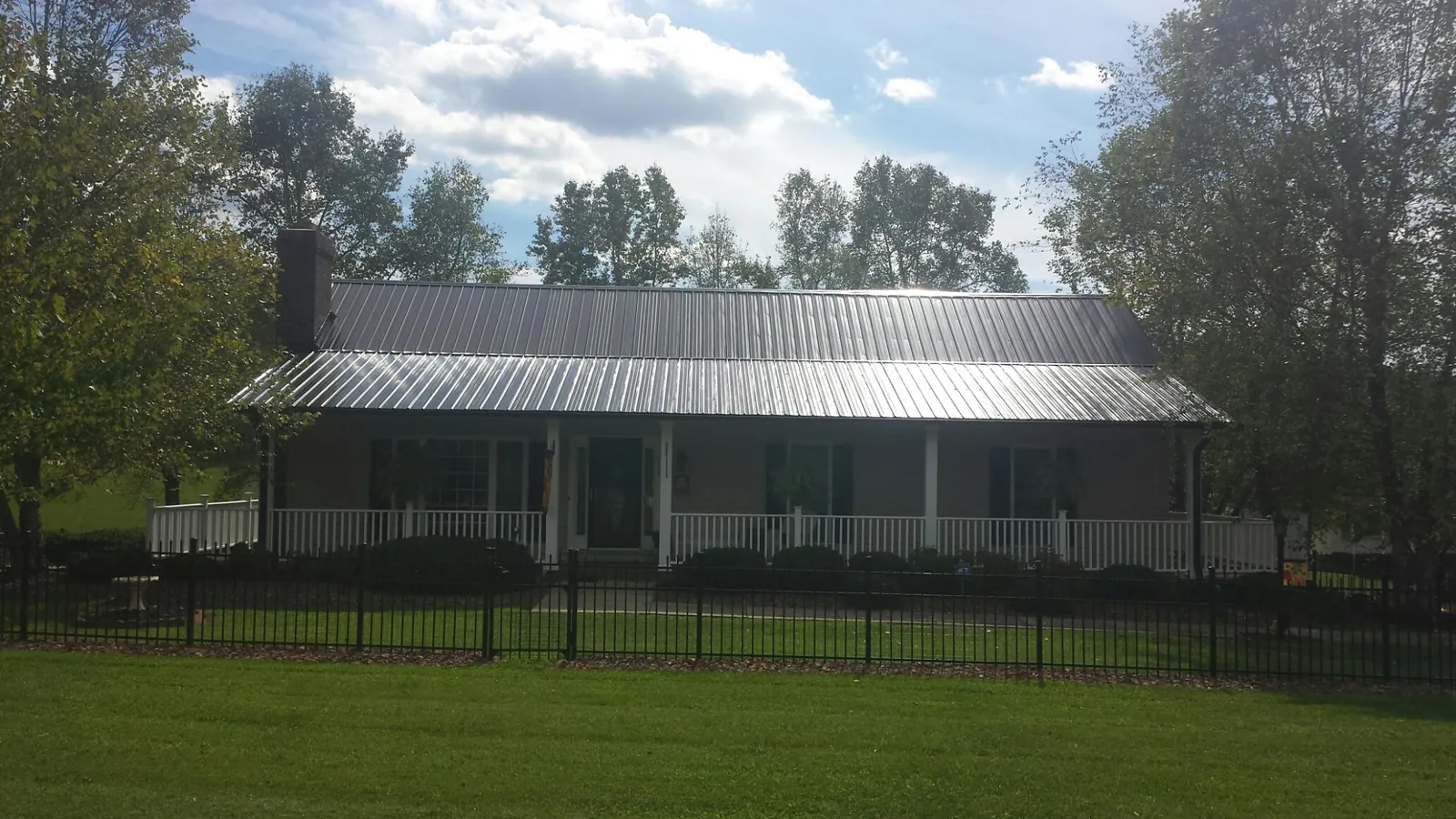 Gray metal roof on a brick ranch with a full width front porch — Gutter Guard Installation work by our crew in Pocono Summit