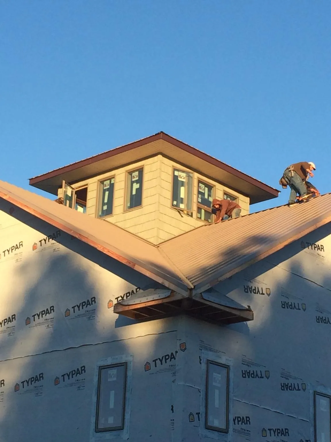 Roofers working around a rooftop cupola on a new metal roof at sunset — Roof Waterproofing in Pocono Summit by Roofing Brothers